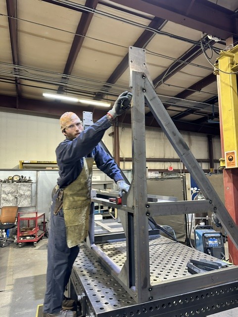 MLC Manufacturing — welder assembling steel frame